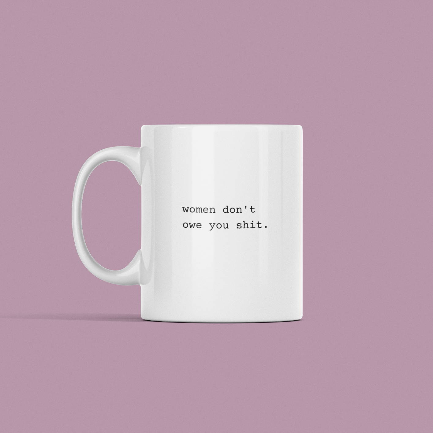 A "Women Don't Owe You Shit" mug with a white base and the text displayed on a purple background.