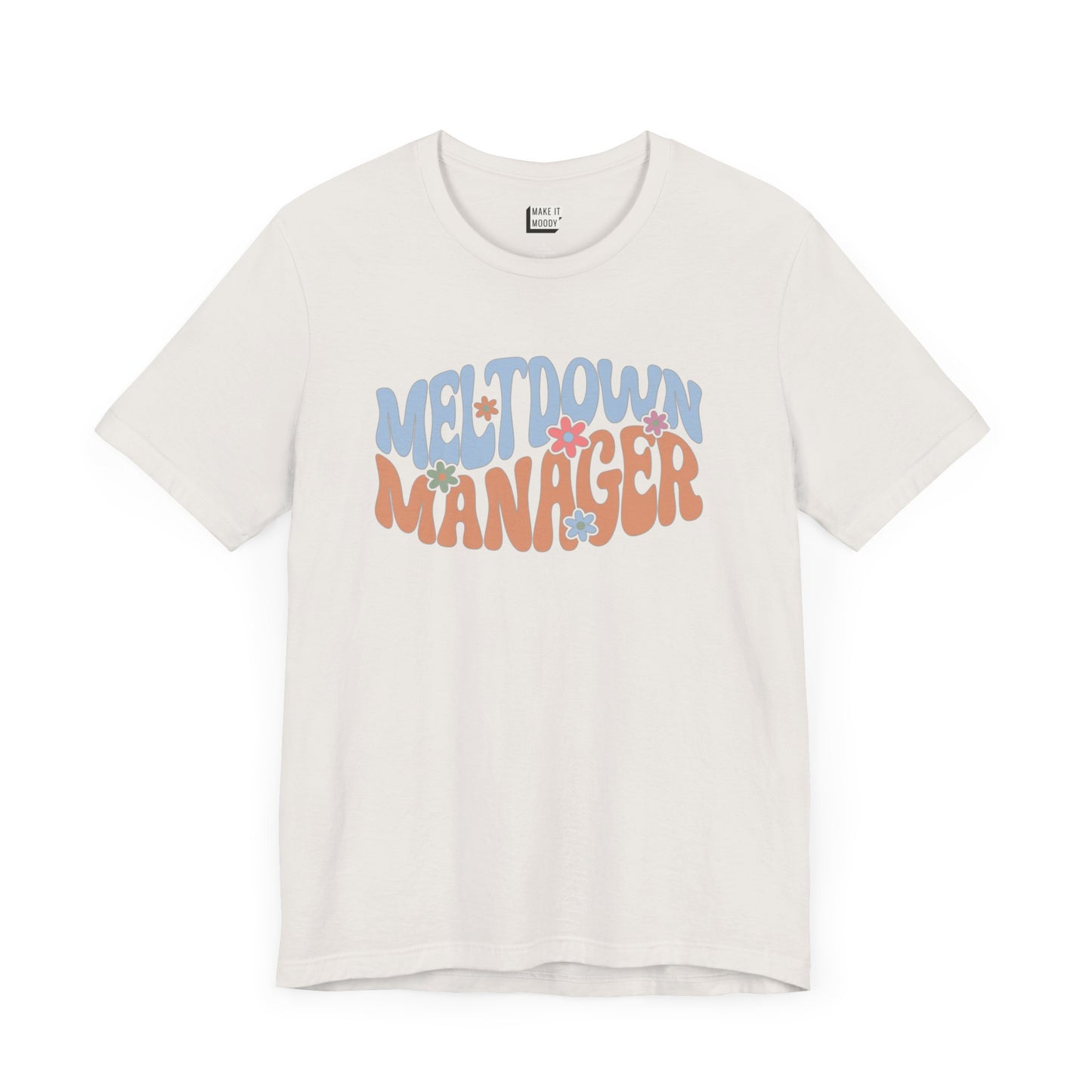 Vintage white colored mom t-shirt featuring the words MELTDOWN MANAGER in a colorful retro-style font with retro flower designs.