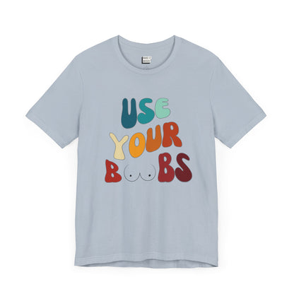 Light blue Breastfeeding T-shirt that says USE YOUR BOOBS in multicolor retro lettering with a minimalistic breast graphic in place of the double O in the word BOOBS.