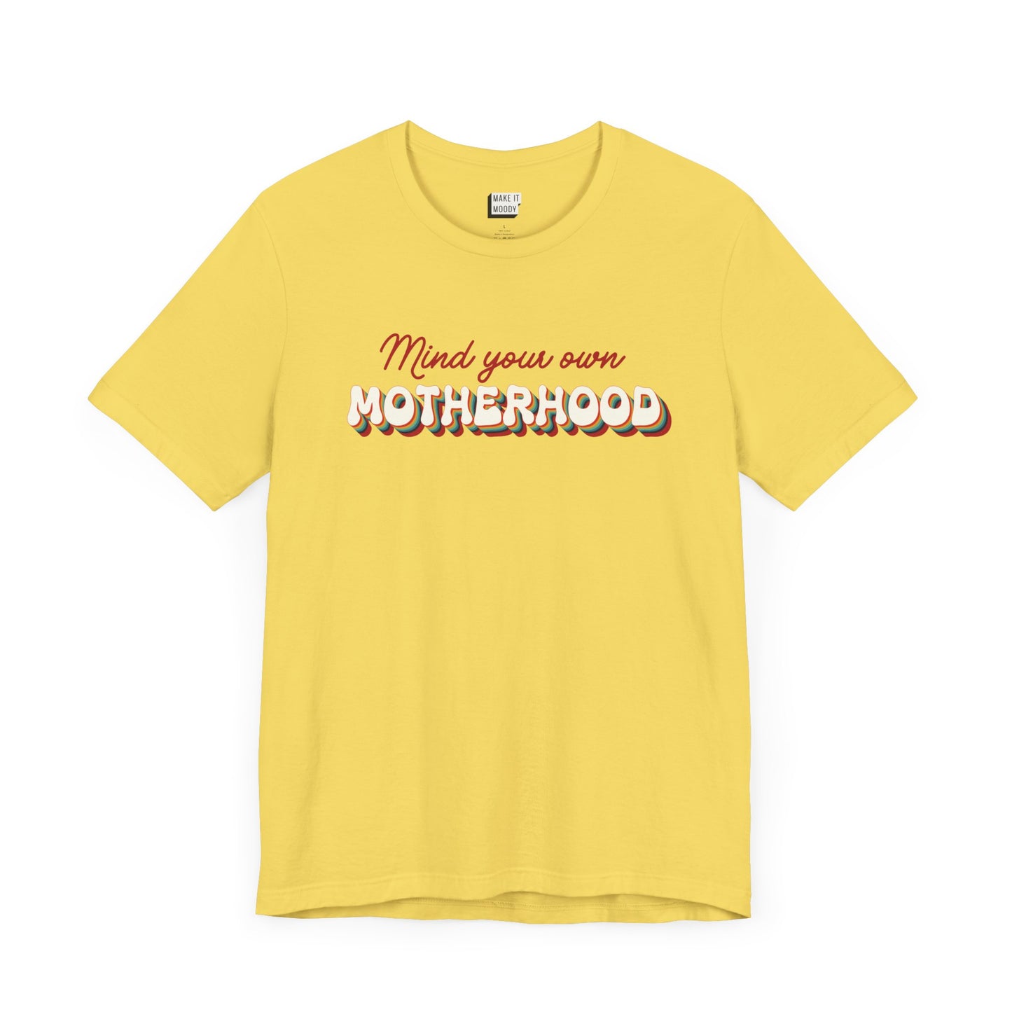 Yellow mom t-shirt featuring the text Mind your own MOTHERHOOD in red and rainbow-colored 3D-style retro letters.