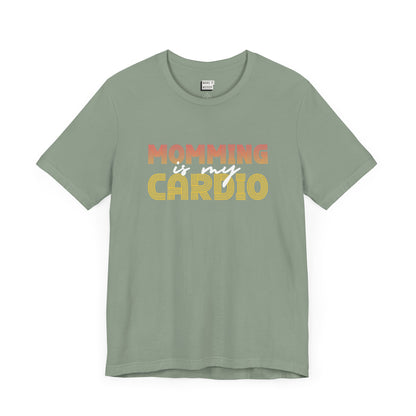 Sage green colored mom t-shirt featuring the text Momming is my Cardio in red, yellow, and white fonts.