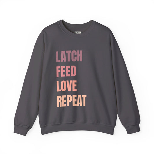 Dark gray breastfeeding sweatshirt that says LATCH FEED LOVE REPEAT in bold pink gradient font.