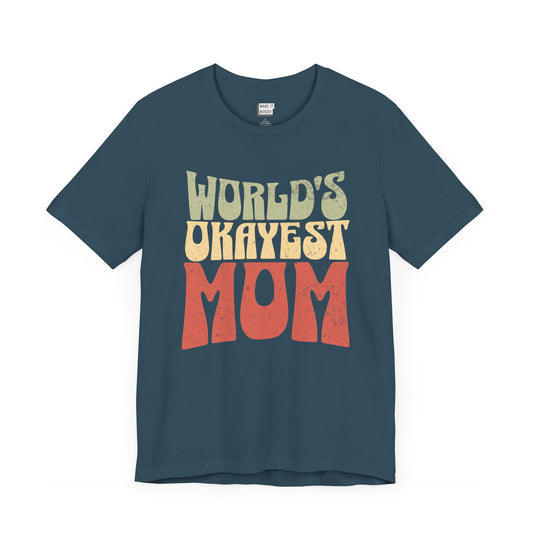 Deep teal mom t-shirt with the text WORLD'S OKAYEST MOM in large retro-style yellow and orange letters on the front.