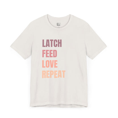 Vintage white breastfeeding t-shirt with the words LATCH FEED LOVE REPEAT in bold pink gradient text.