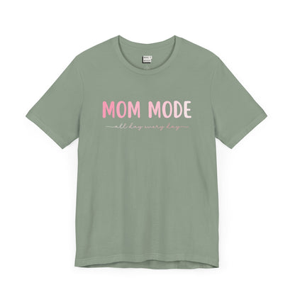 Sage green-colored mom t-shirt with the text MOM MODE all day every day in pink and white font.