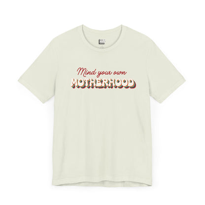 Light green mom t-shirt featuring the text Mind your own MOTHERHOOD in red and rainbow colored 3D-style retro letters.