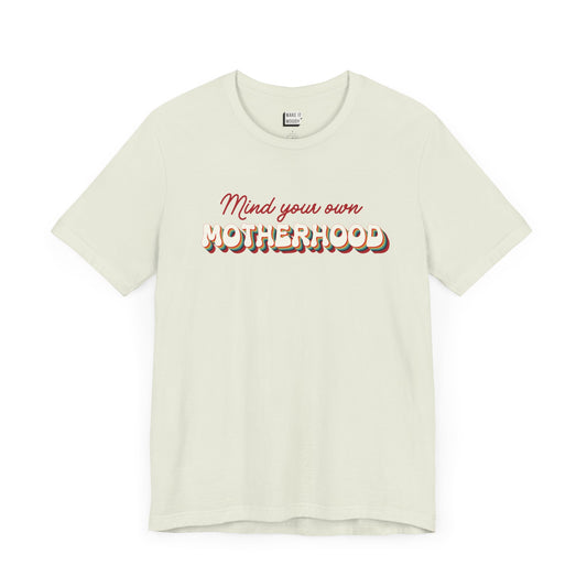 Light green mom t-shirt featuring the text Mind your own MOTHERHOOD in red and rainbow colored 3D-style retro letters.