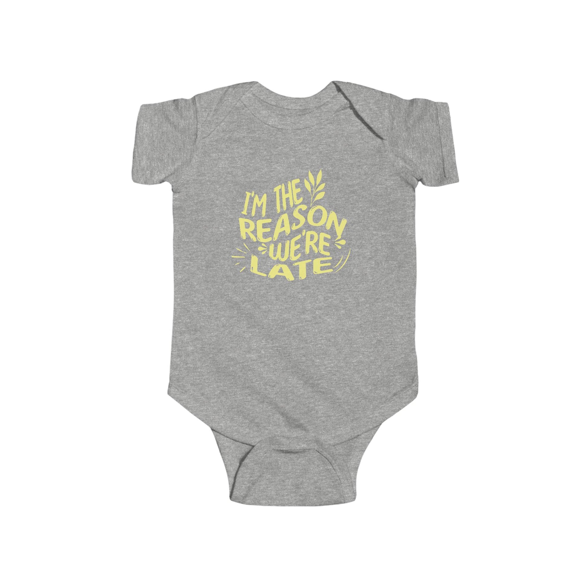 heather grey infant bodysuit that says I'M THE REASON WE'RE LATE in yellow wavy lettering on the front.