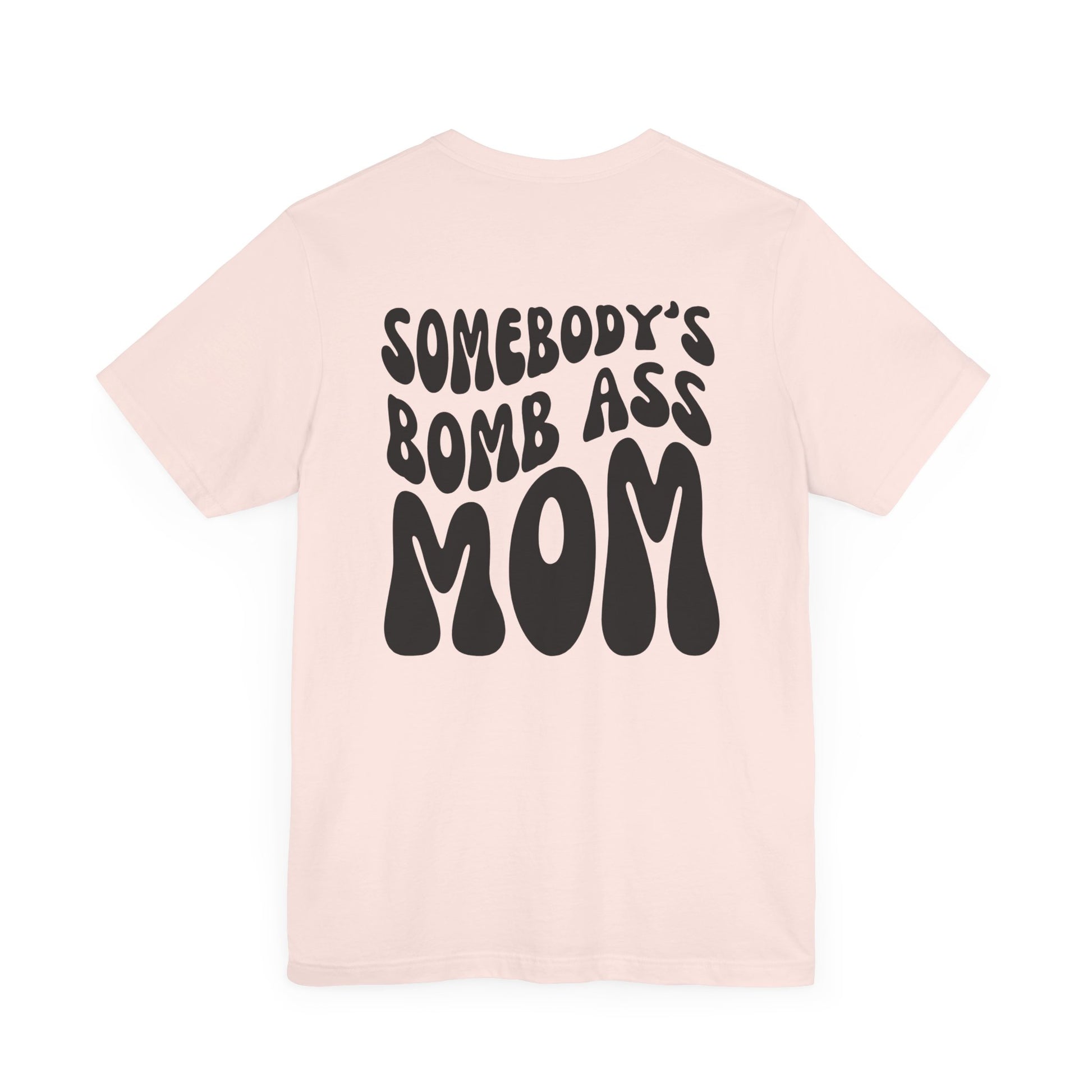 Soft pink mom t-shirt featuring bold black retro text on the back that reads SOMEBODY'S BOMB ASS MOM.