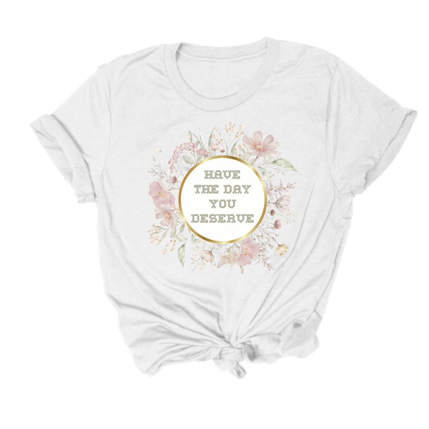 Introducing the "Have The Day You Deserve Tee," a white T-shirt featuring a floral design and the text "HAVE THE DAY YOU DESERVE" prominently displayed in the center, complete with a stylish tie at the bottom.