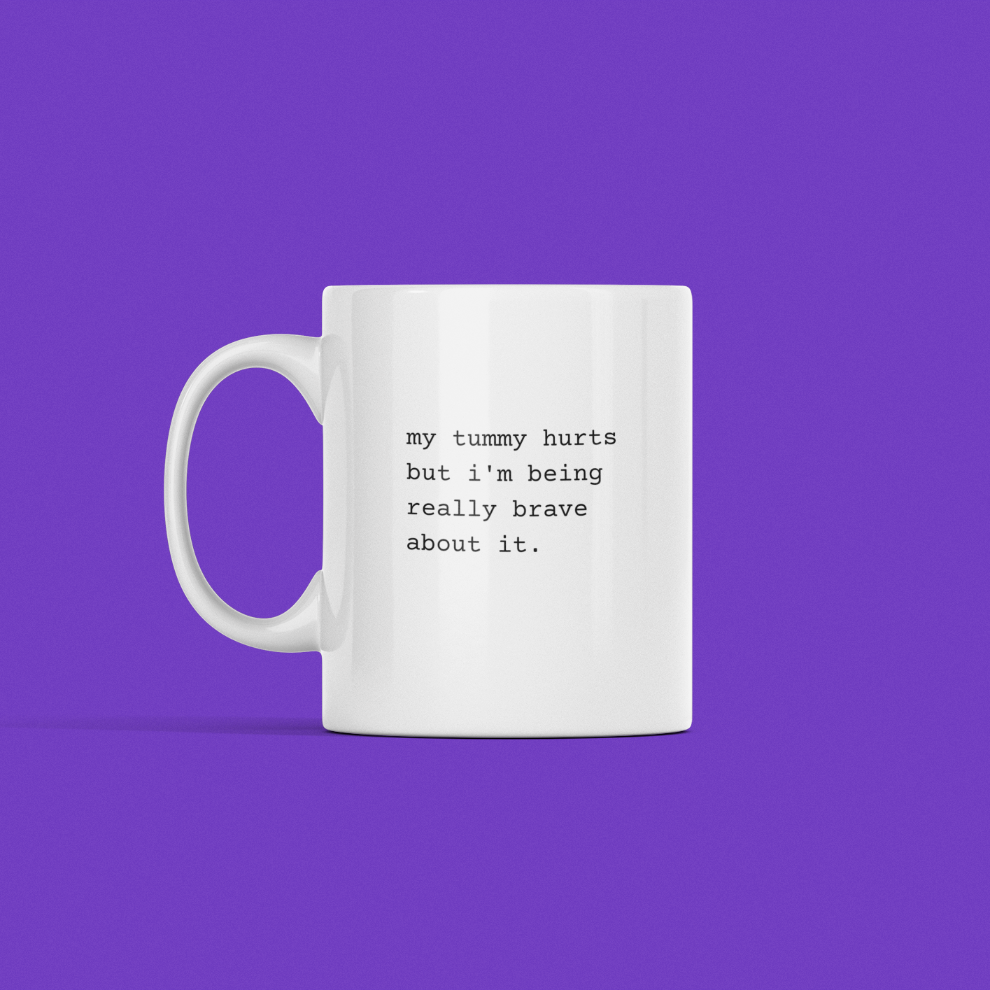 A My Tummy Hurts Mug with a white exterior and the text "my tummy hurts but i'm being really brave about it" on a purple background.