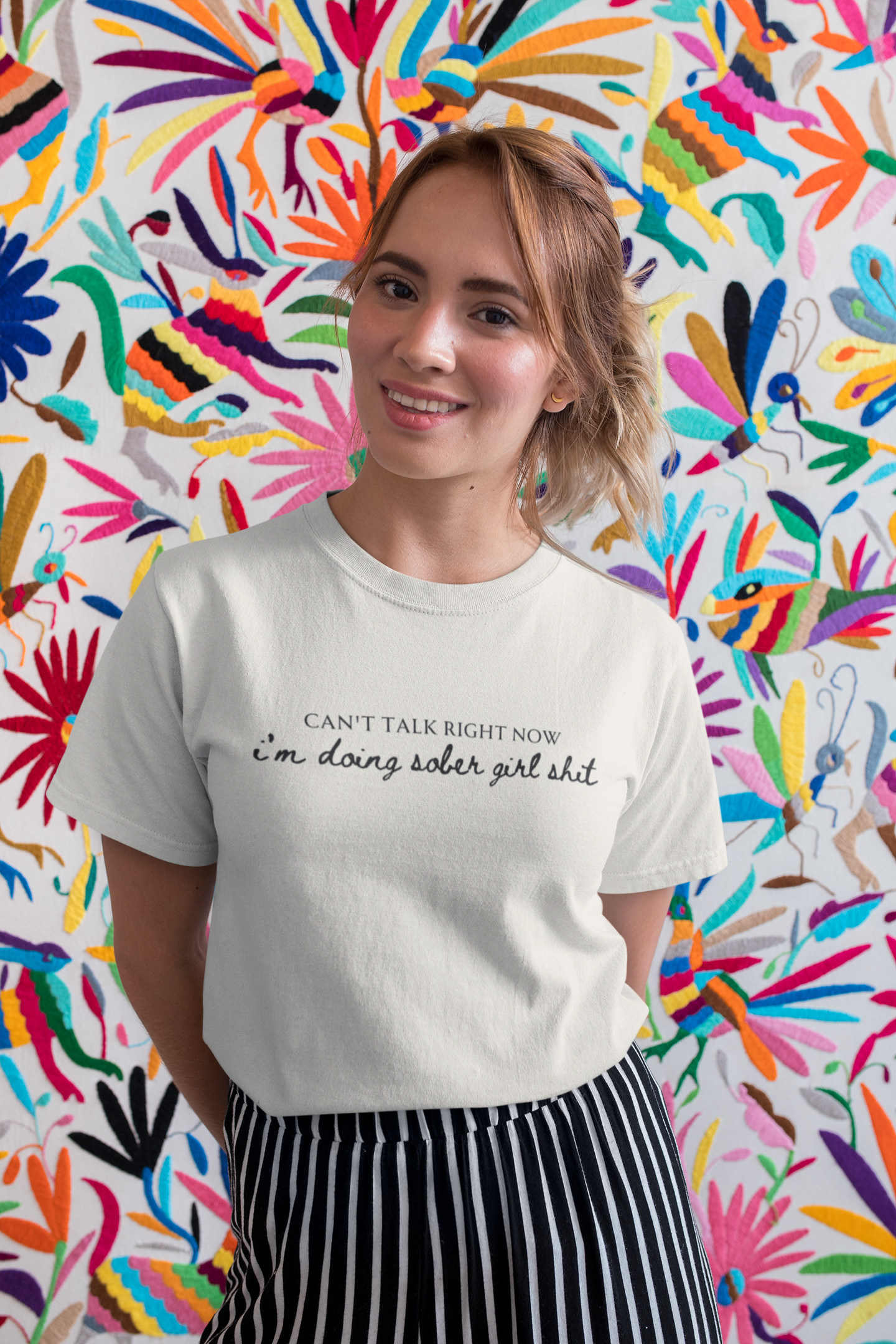 girl wearing a sobriety themed t shirt that says "can't talk right now, I'm doing sober girl shit."