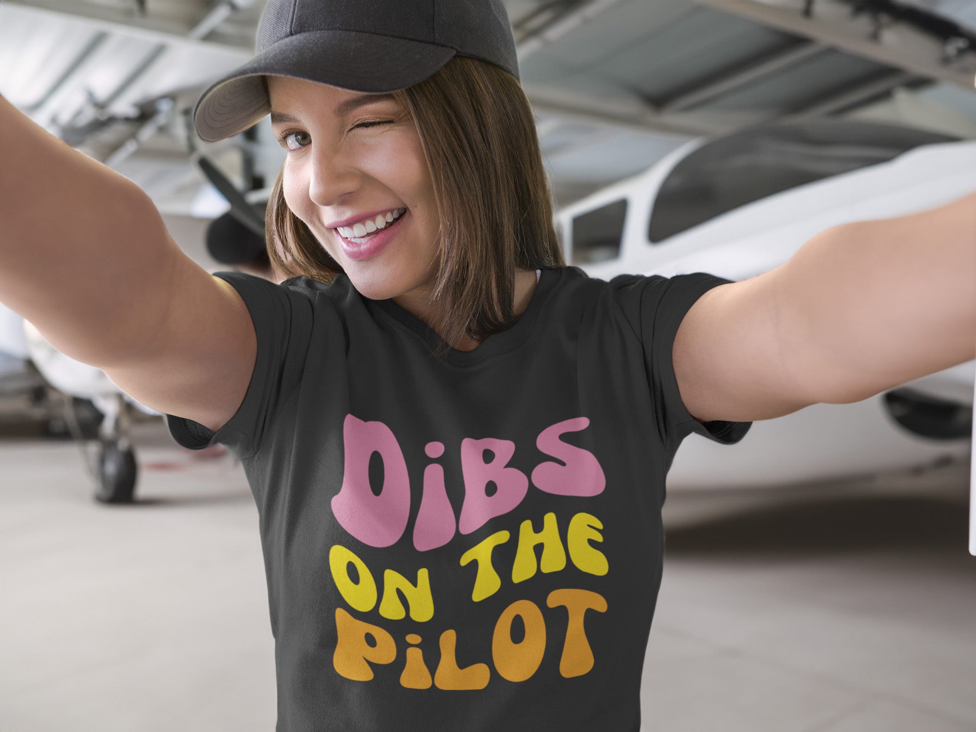 woman wearing a funny tshirt for pilot wives or girlfriends that says "dibs on the pilot"